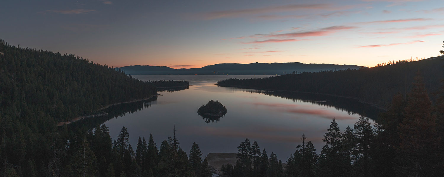 A lake surrounded by forest at dusk