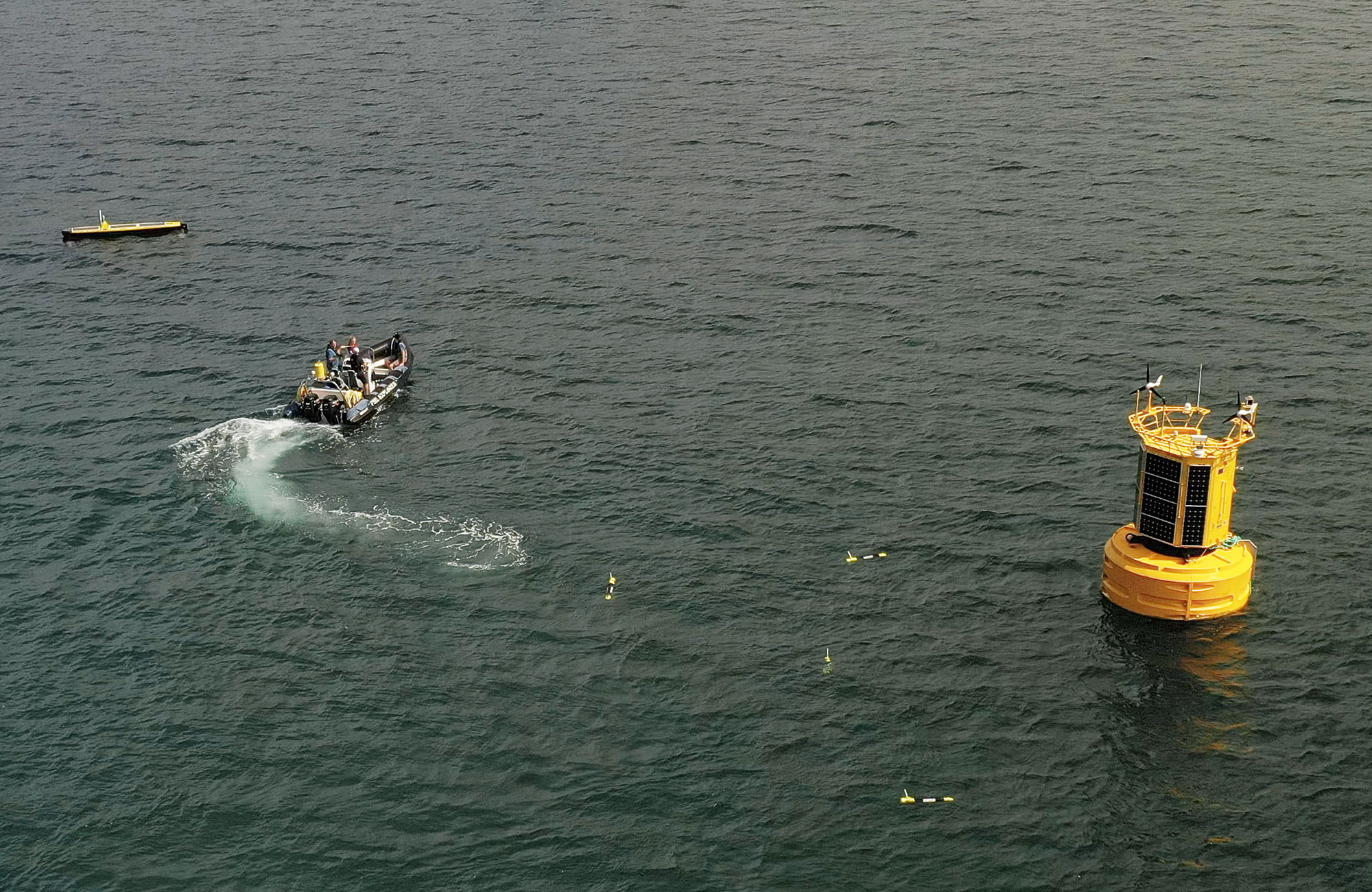 Marine data buoy and autonomous gliders being deployed into the ocean