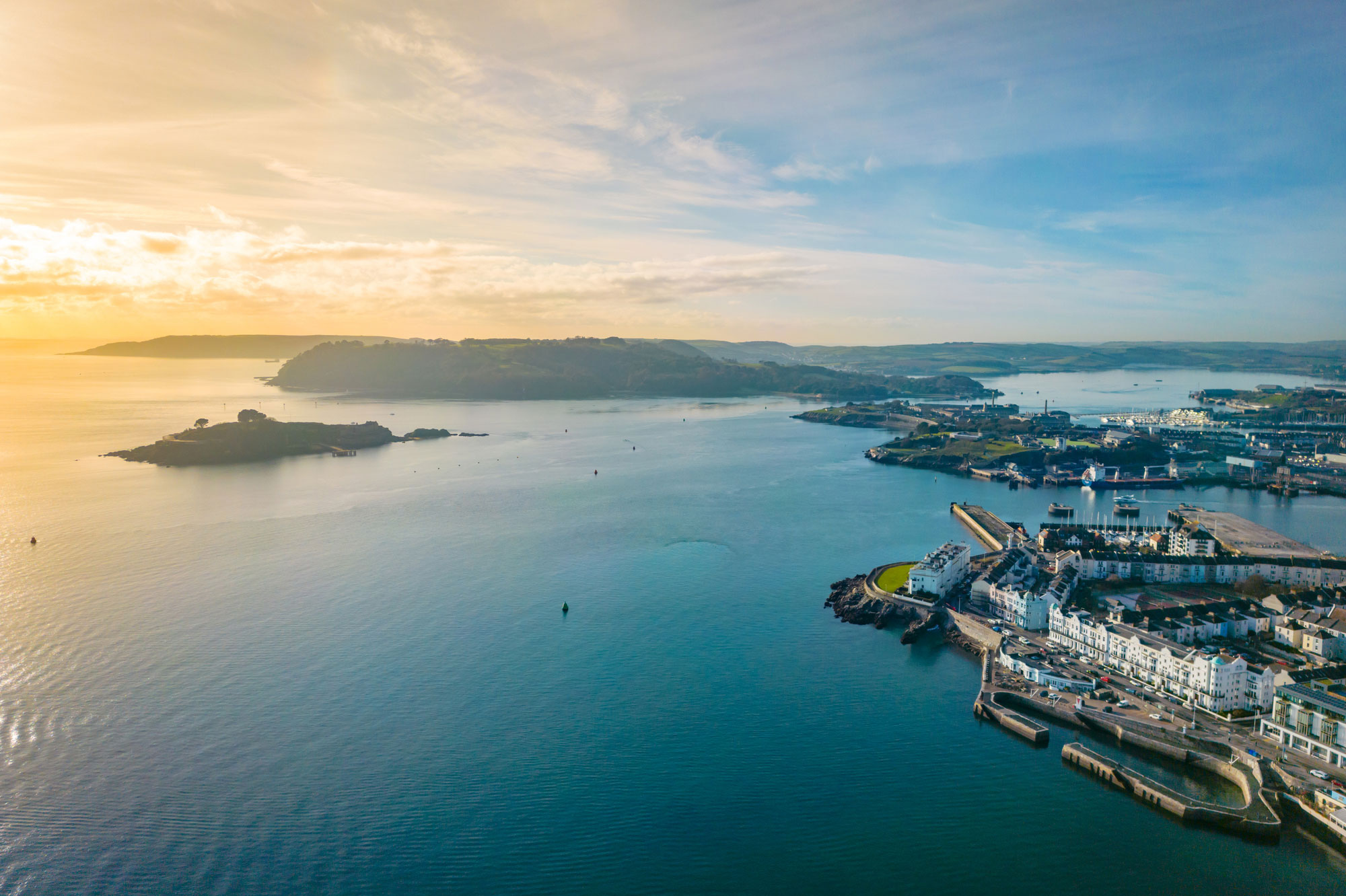 High angle Drone shot of Plymouth Sound with orange sunset in background