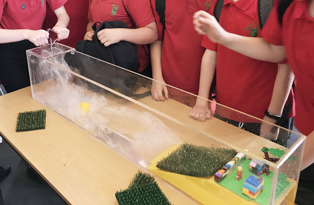 First tank demonstrating sea defences using lego town School children using a tank demonstrating flood defences with lego